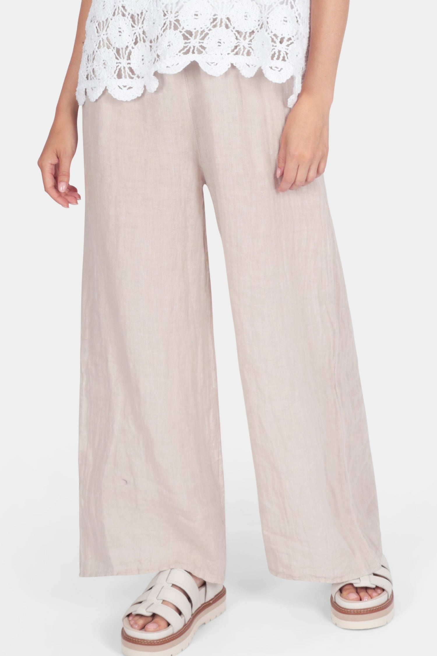 Linen Straight Leg Trouser in beige with elasticated waistband and wide leg, worn with white crochet top and sandals.