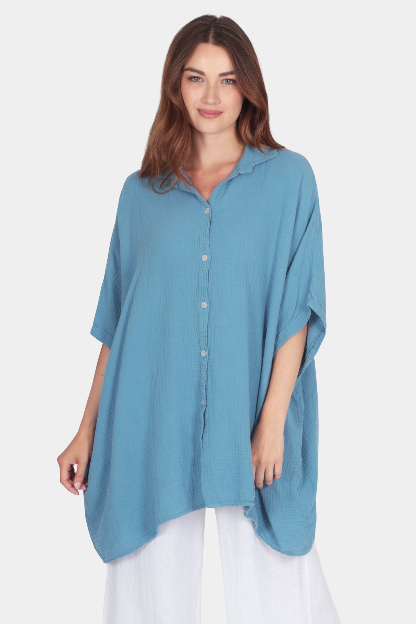 Bella Relaxed Drape Cotton Shirt in blue with button front, short sleeves, and asymmetrical curved hem worn by woman.