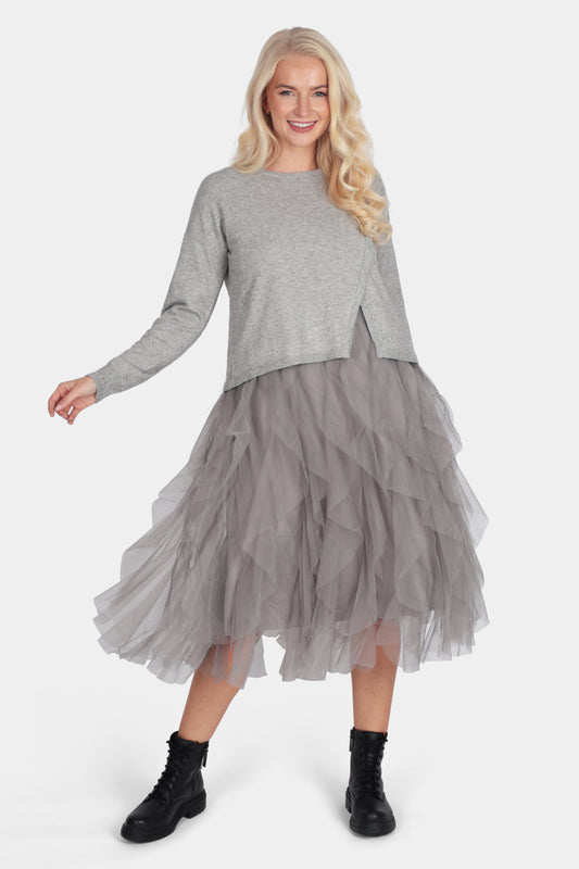 Woman wearing a gray sweater and tulle skirt on a white background