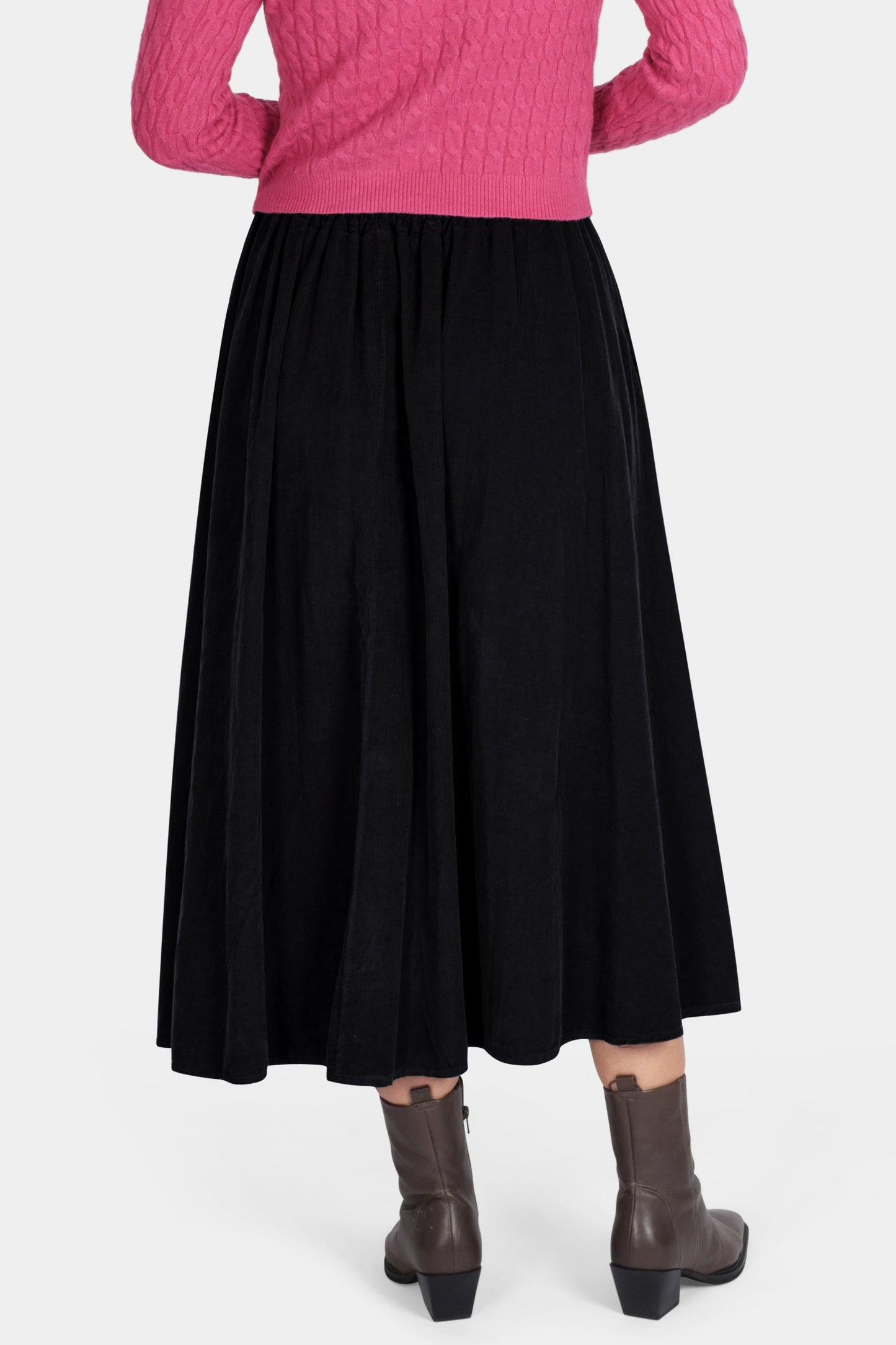 Person wearing a pink sweater and black skirt on a white background