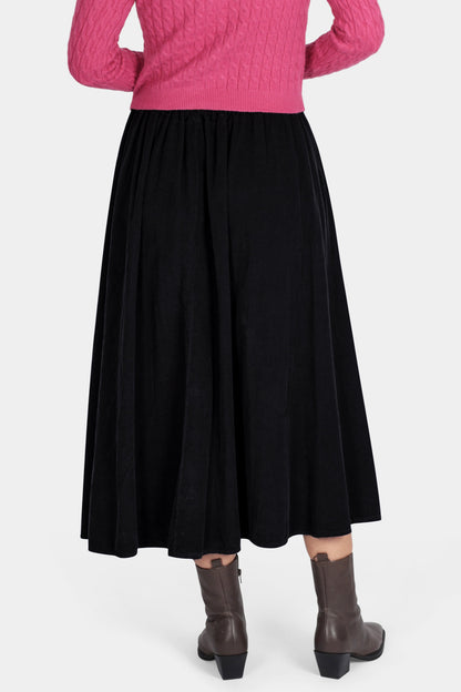 Person wearing a pink sweater and black skirt on a white background