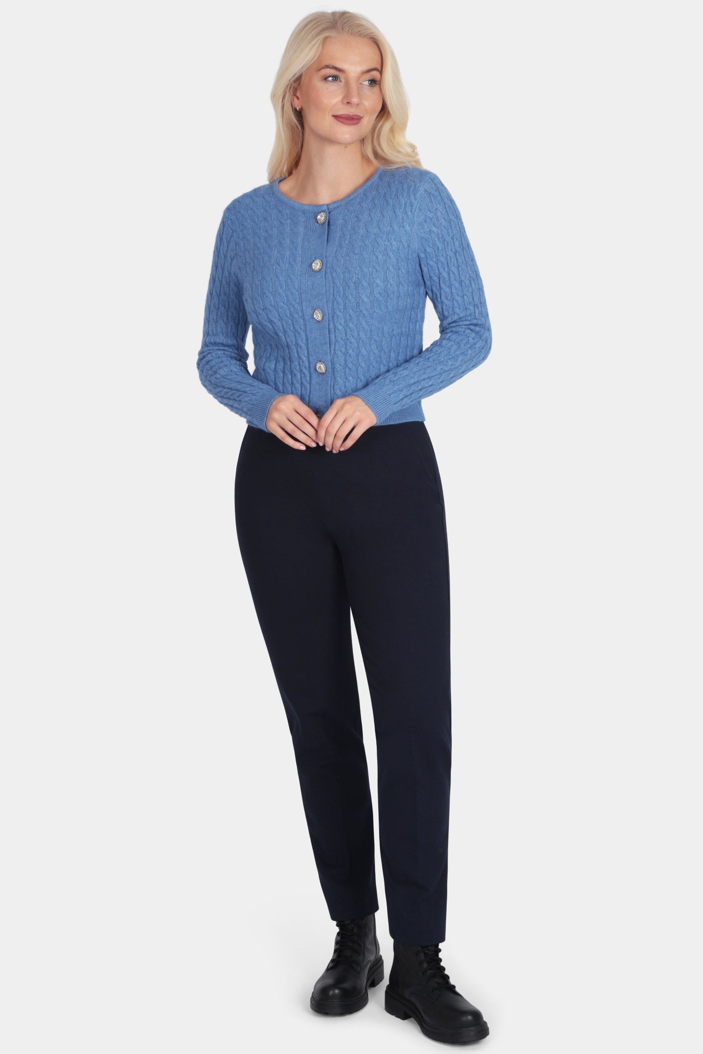 Woman wearing a blue cardigan and black pants on a white background