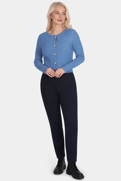 Woman wearing a blue cardigan and black pants on a white background
