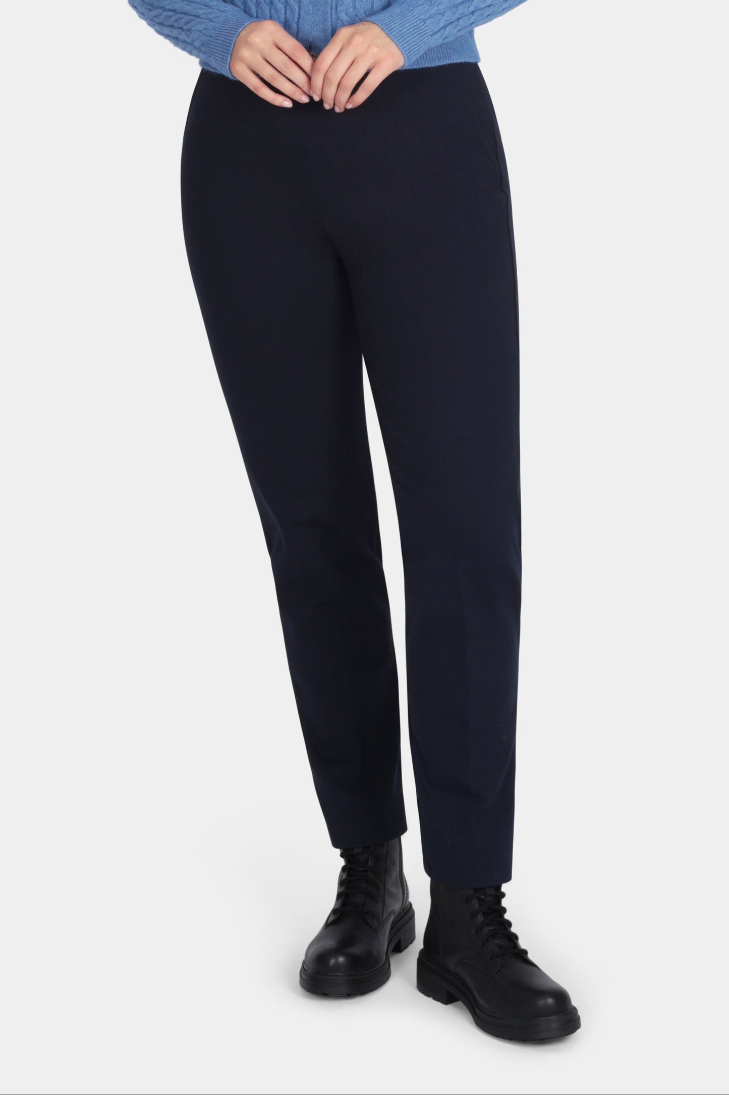 Woman wearing a blue cardigan and black pants on a white background