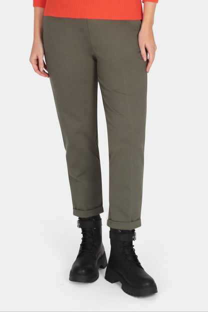 Woman wearing an orange sweater and green pants on a white background