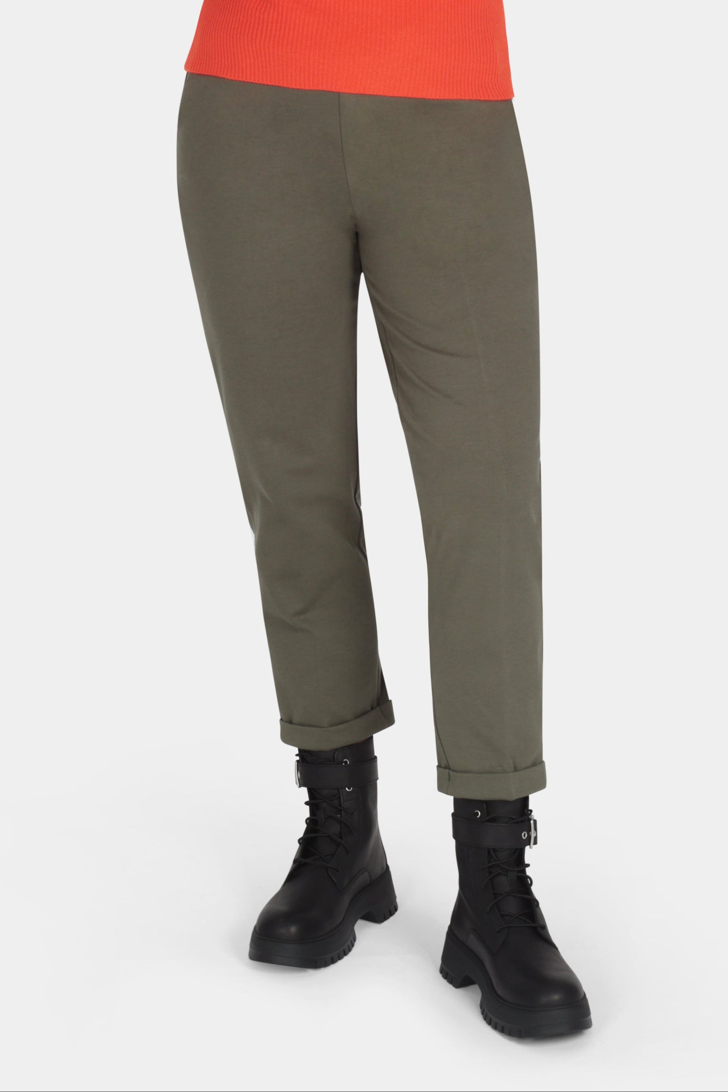 Woman wearing an orange sweater and green pants on a white background