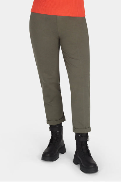 Woman wearing an orange sweater and green pants on a white background