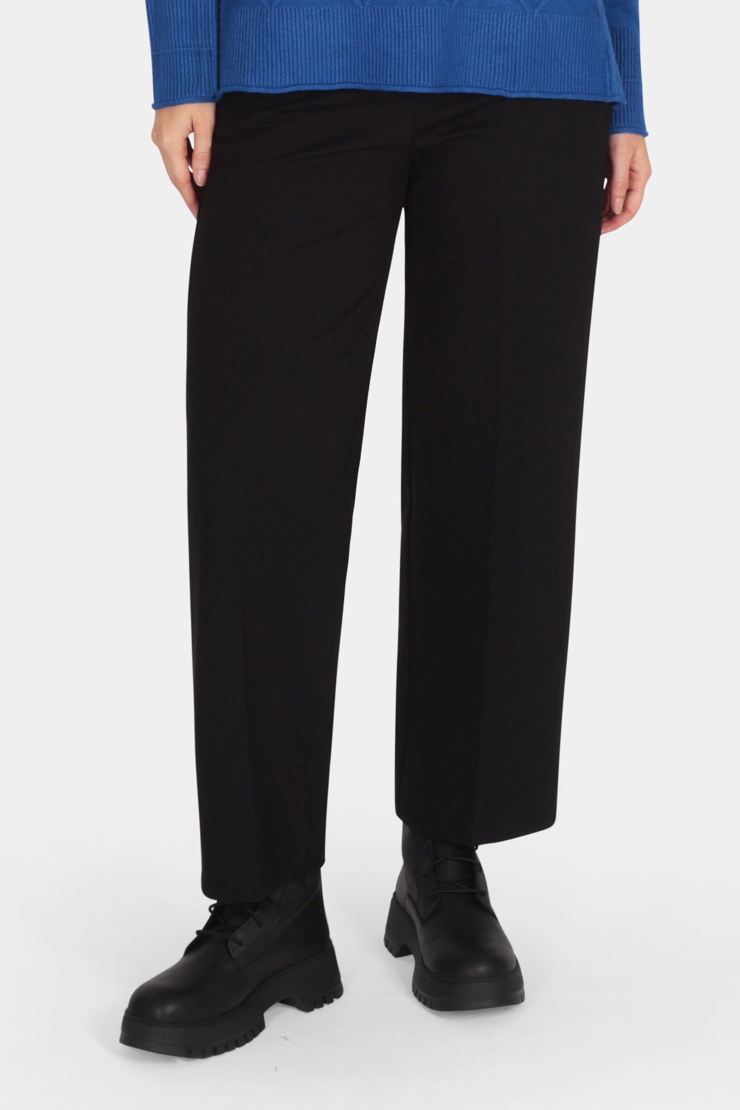 Woman wearing a blue sweater and black pants on a white background