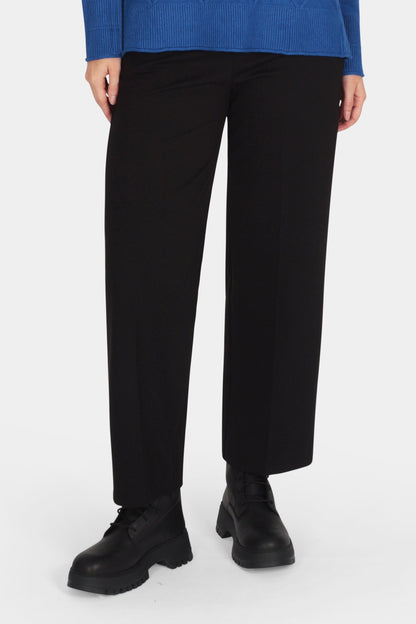 Woman wearing a blue sweater and black pants on a white background