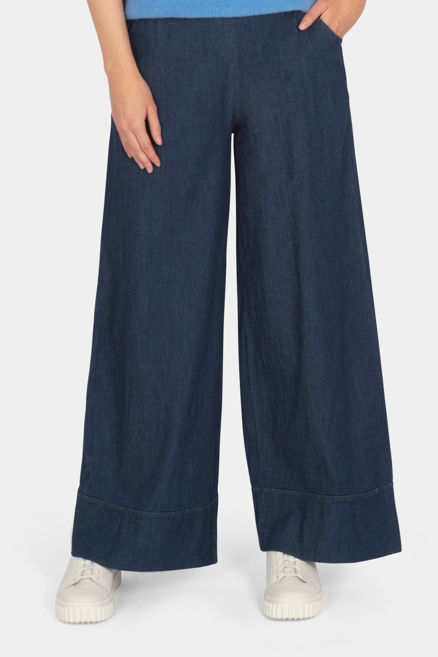 Woman wearing a blue top and navy wide-leg pants on a white background