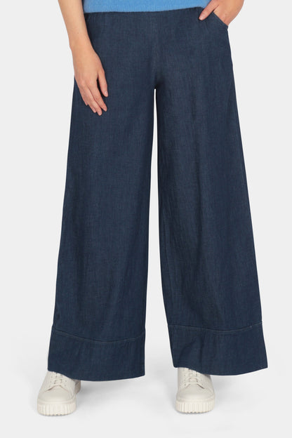 Woman wearing a blue top and navy wide-leg pants on a white background