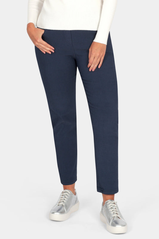 Woman wearing a white sweater and navy pants on a white background