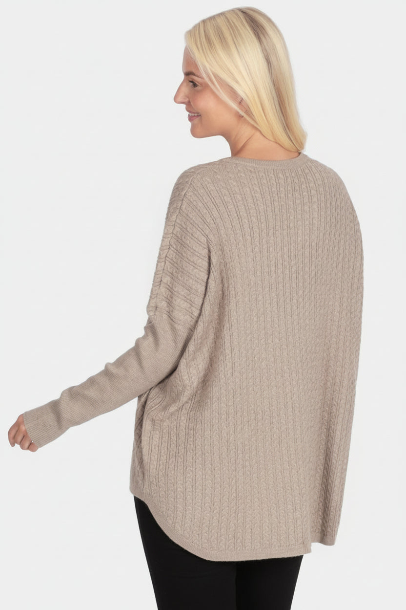 Woman wearing a beige sweater and green pants on a white background