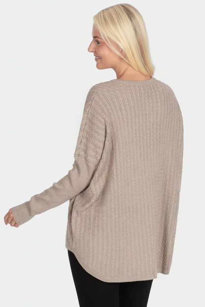 Woman wearing a beige sweater and green pants on a white background