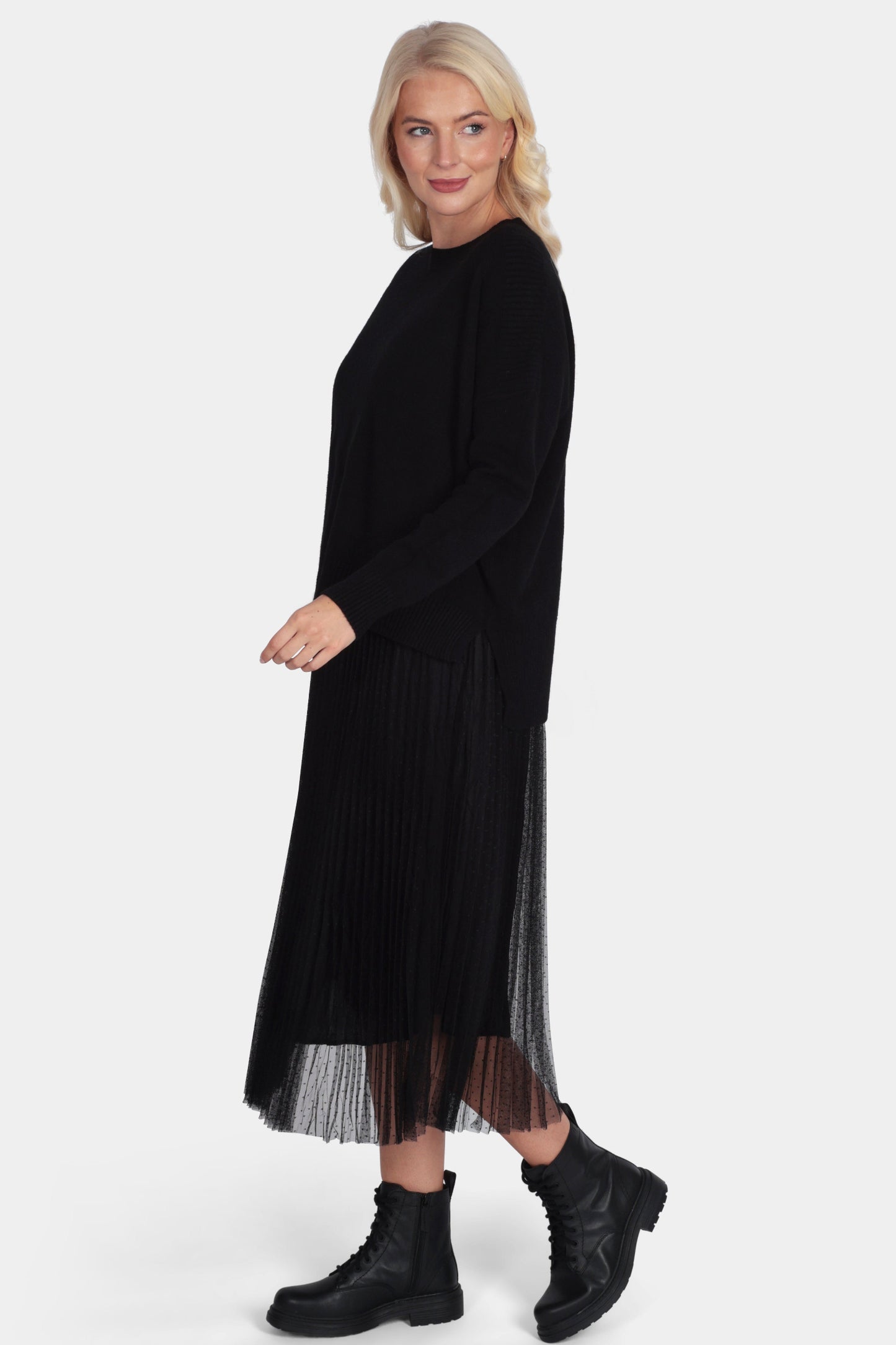 Woman wearing a black dress with sheer overlay on a white background