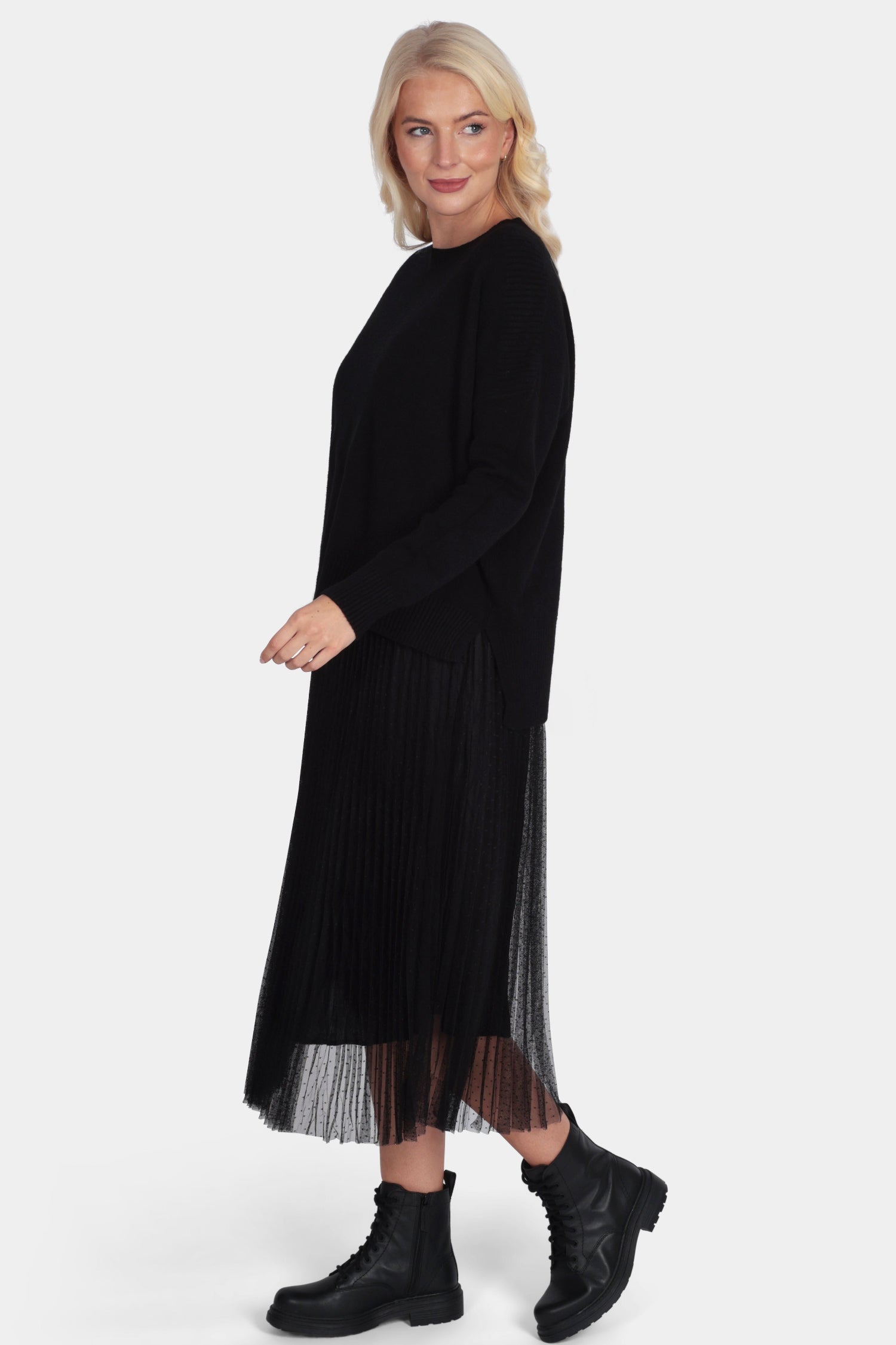 Woman wearing a black dress with sheer overlay on a white background