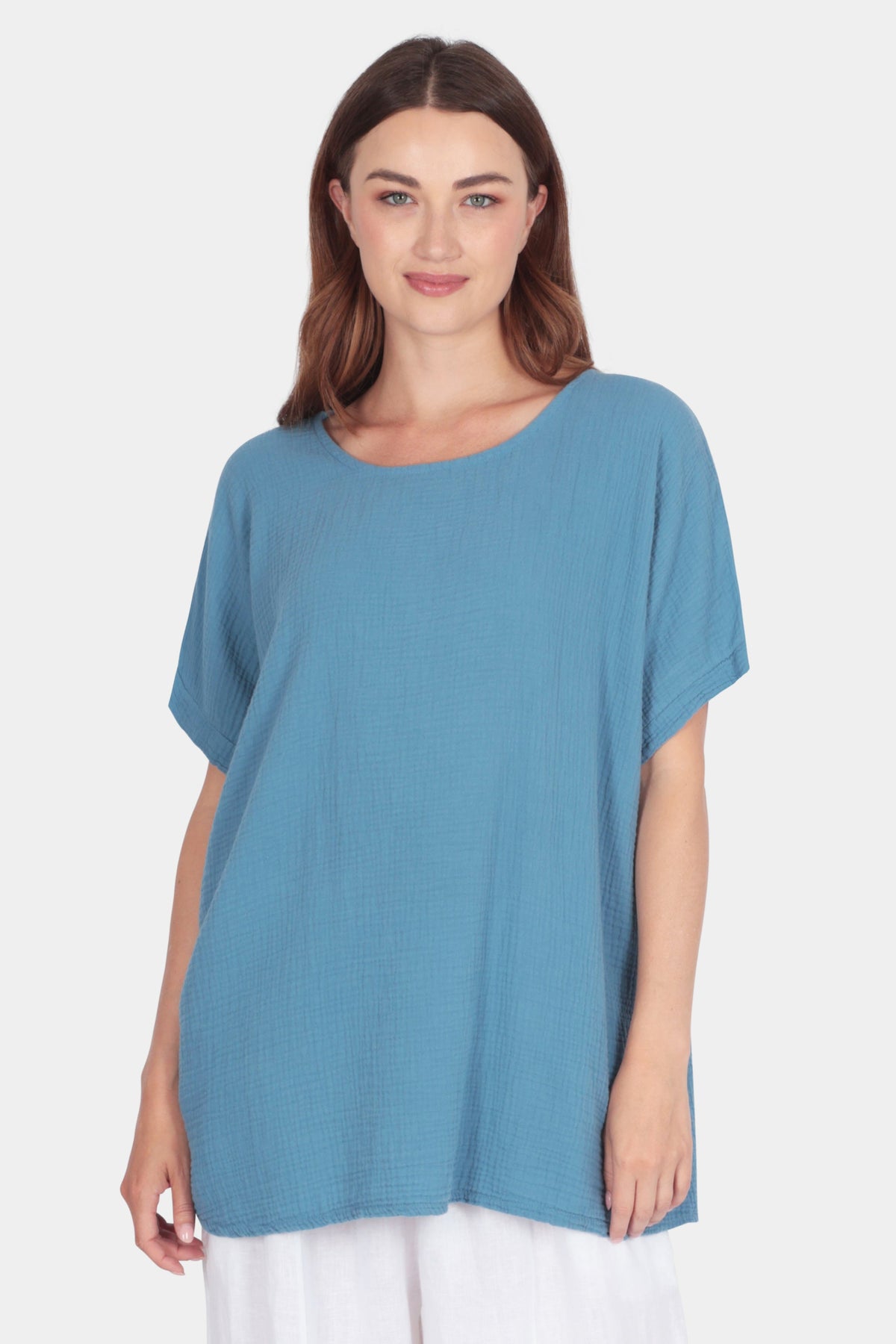 Woman wearing a blue Aria Relaxed Cotton Tee with scoop neckline and short sleeves against a plain background.