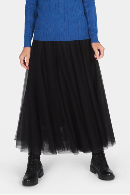 Woman wearing a blue turtleneck sweater and black pleated skirt on a white background