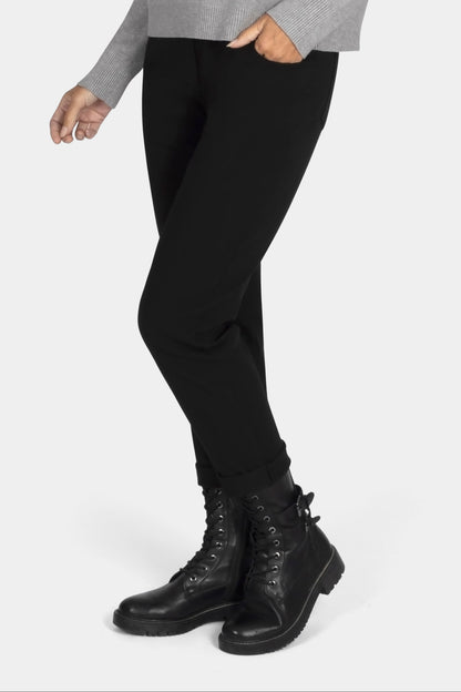 Woman wearing a gray sweater, black leggings, and black boots on a white background