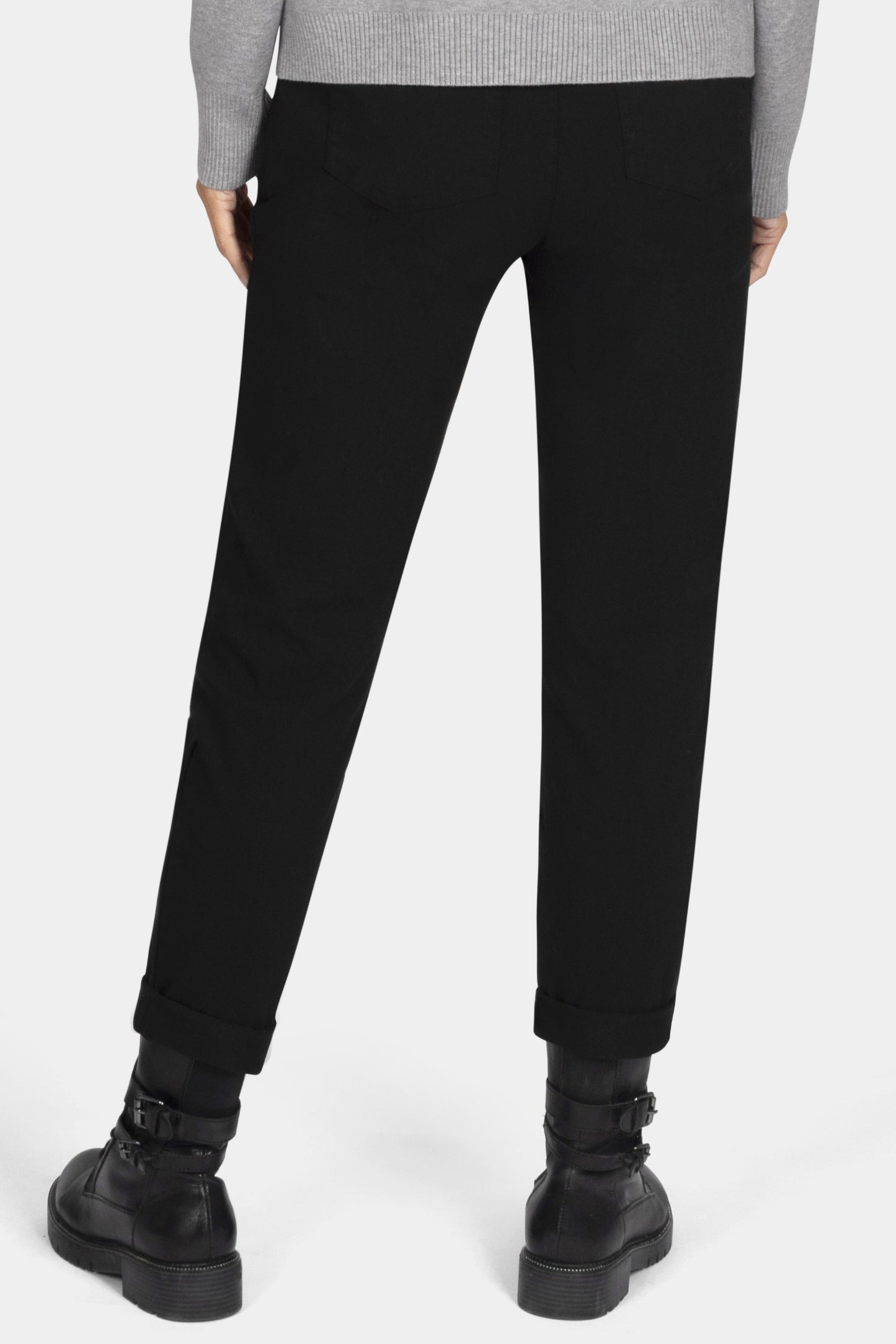 Person wearing a gray sweater and black pants on a white background