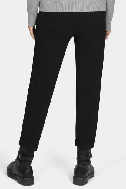 Person wearing a gray sweater and black pants on a white background