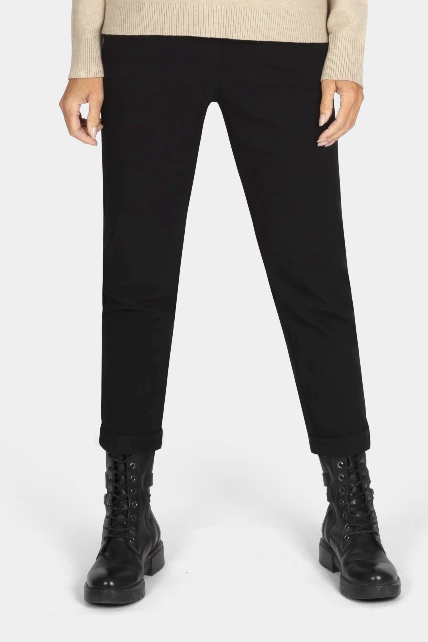 Woman wearing a beige sweater and black pants on a white background