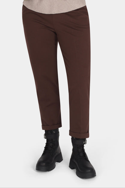 Woman wearing a green sweater and brown pants on a white background