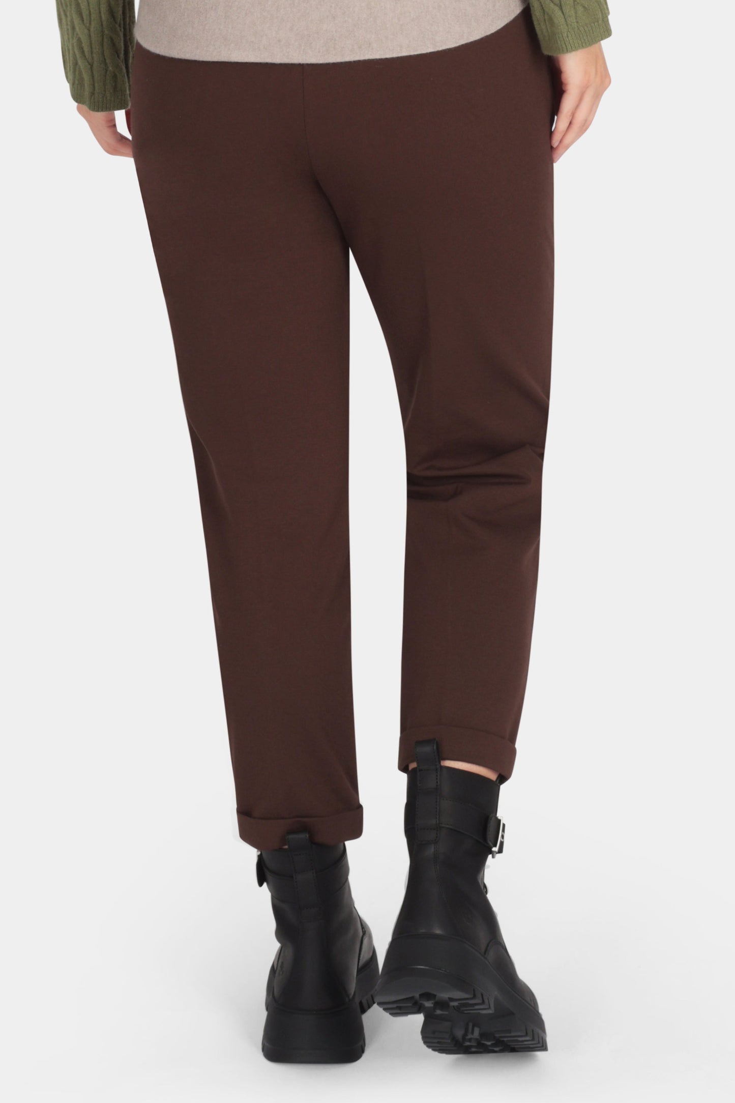 Person wearing a green sweater and brown pants on a white background