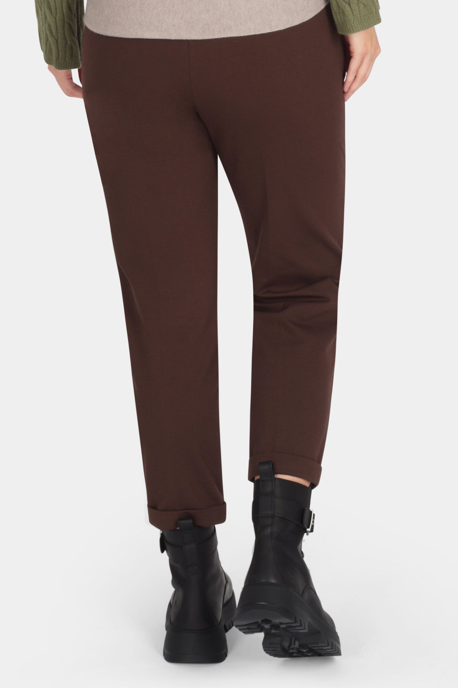 Person wearing a green sweater and brown pants on a white background