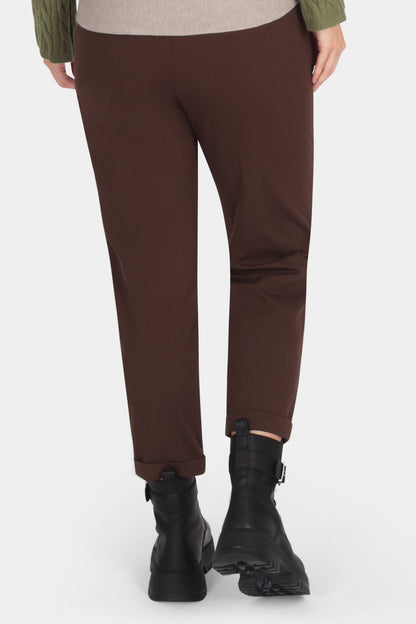 Person wearing a green sweater and brown pants on a white background