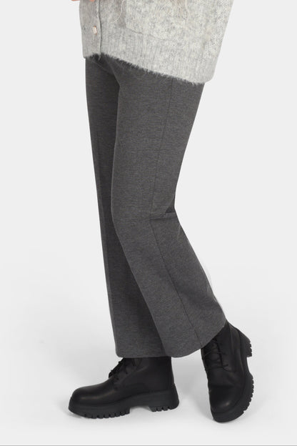 Woman wearing a gray cardigan, gray pants, and black shoes on a white background