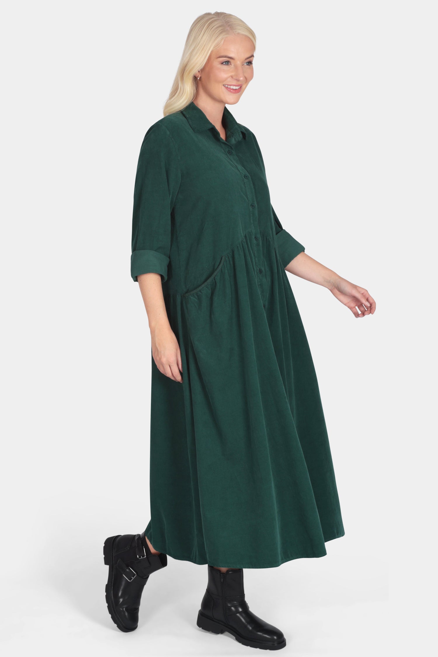 Woman wearing a green dress with black boots on a white background
