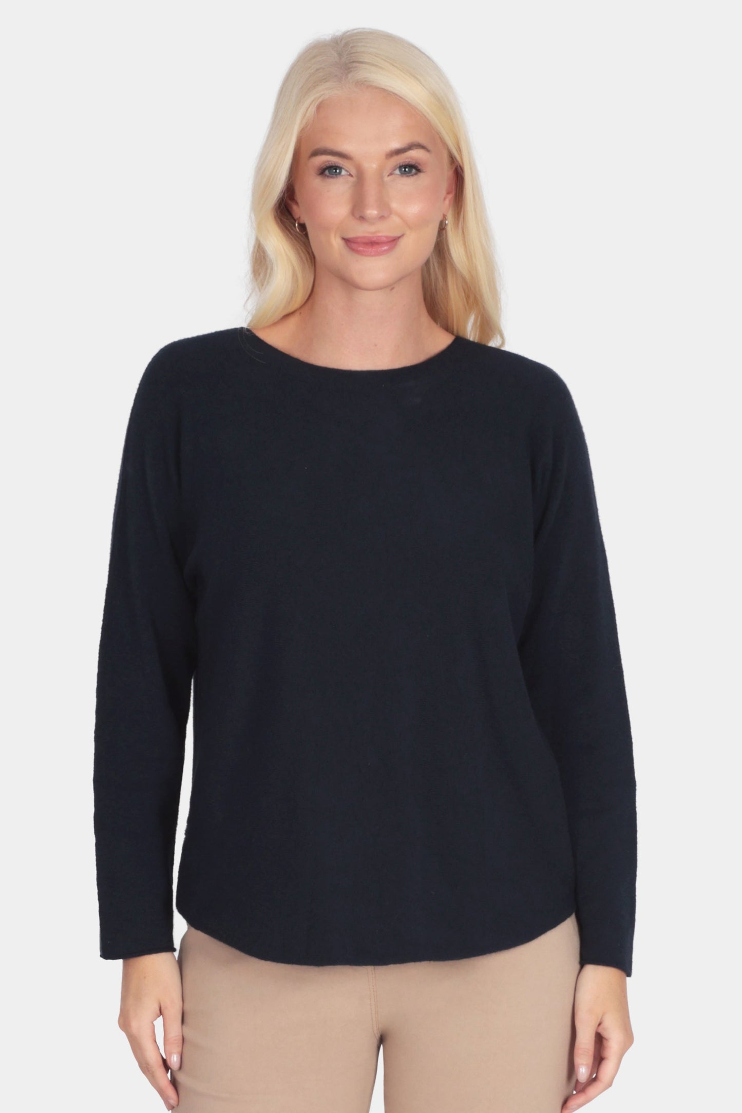 Woman wearing a navy long-sleeve soft fine knit top and camel beige pants 