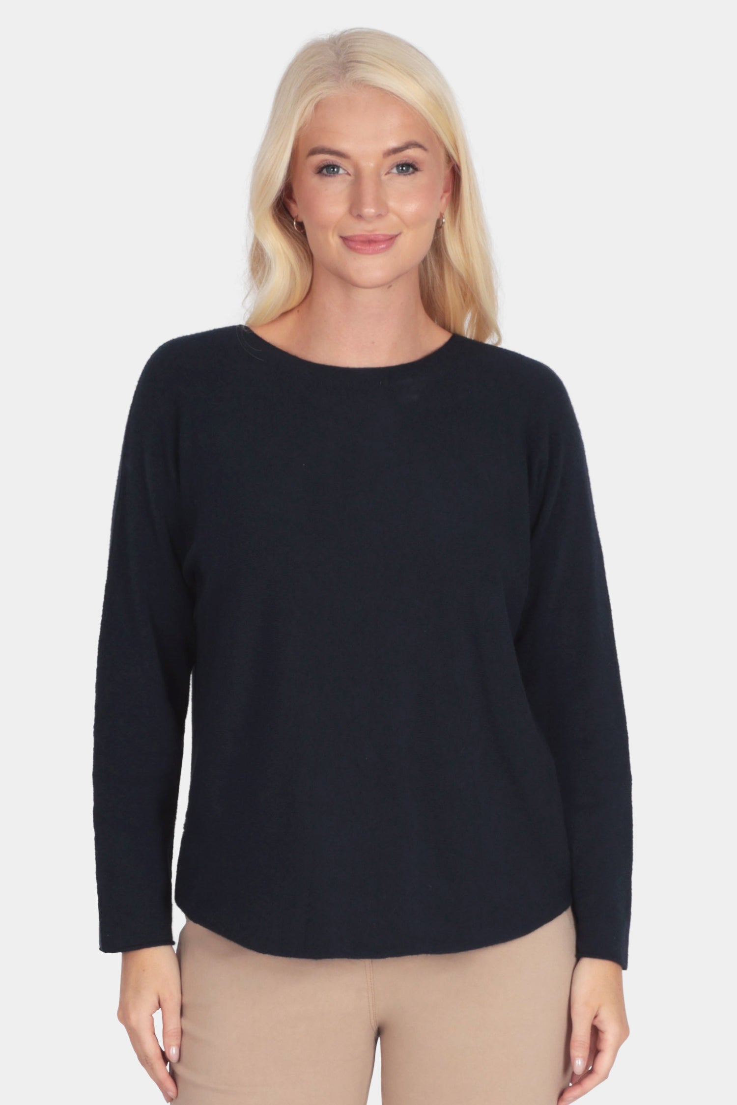 Woman wearing a navy long-sleeve soft fine knit top and camel beige pants 