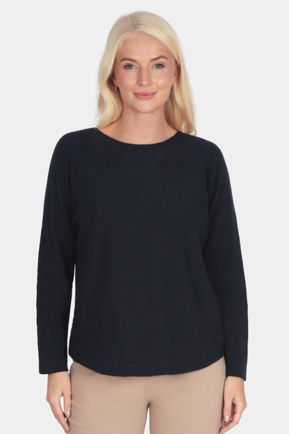 Woman wearing a navy long-sleeve soft fine knit top and camel beige pants 