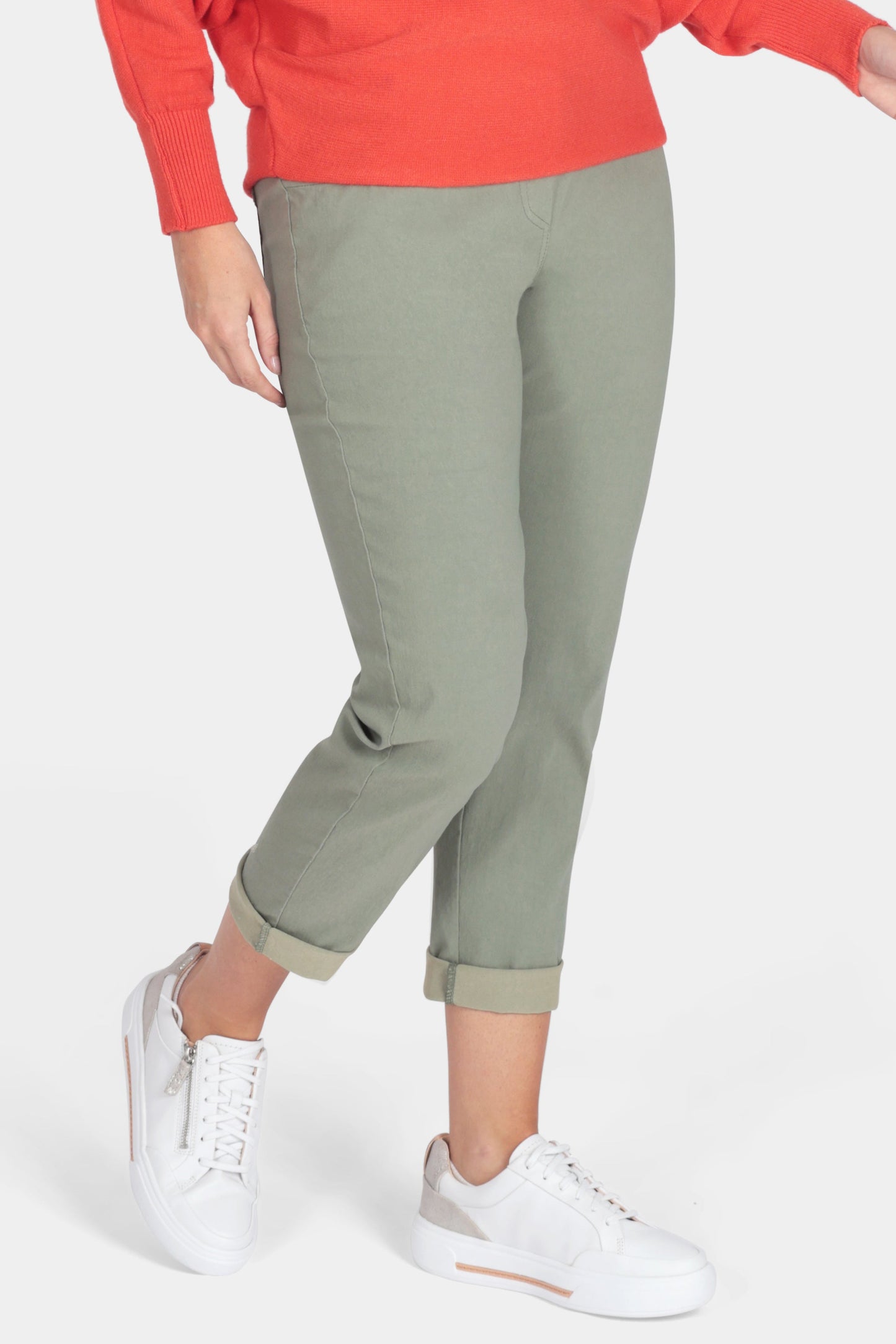 Woman wearing a red sweater and green pants on a white background