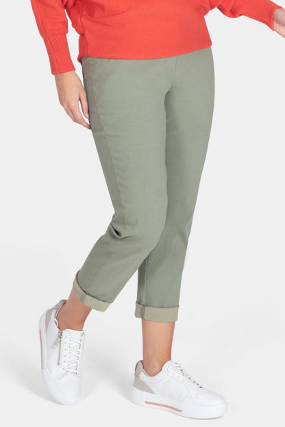 Woman wearing a red sweater and green pants on a white background