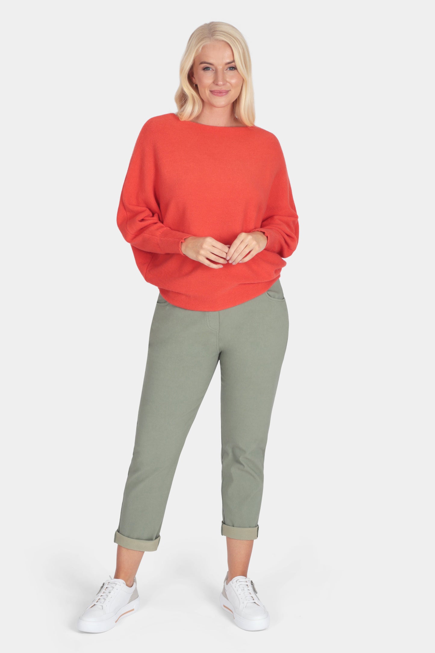 Woman wearing a red sweater and green pants on a white background