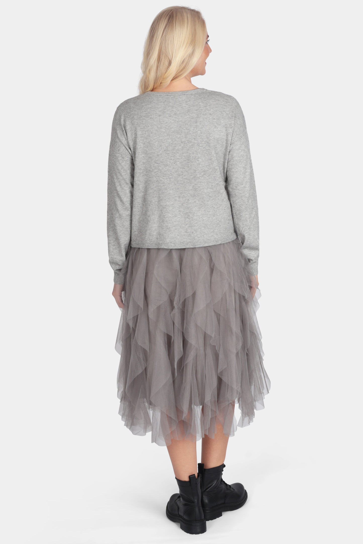 Woman wearing a gray sweater and layered skirt on a white background