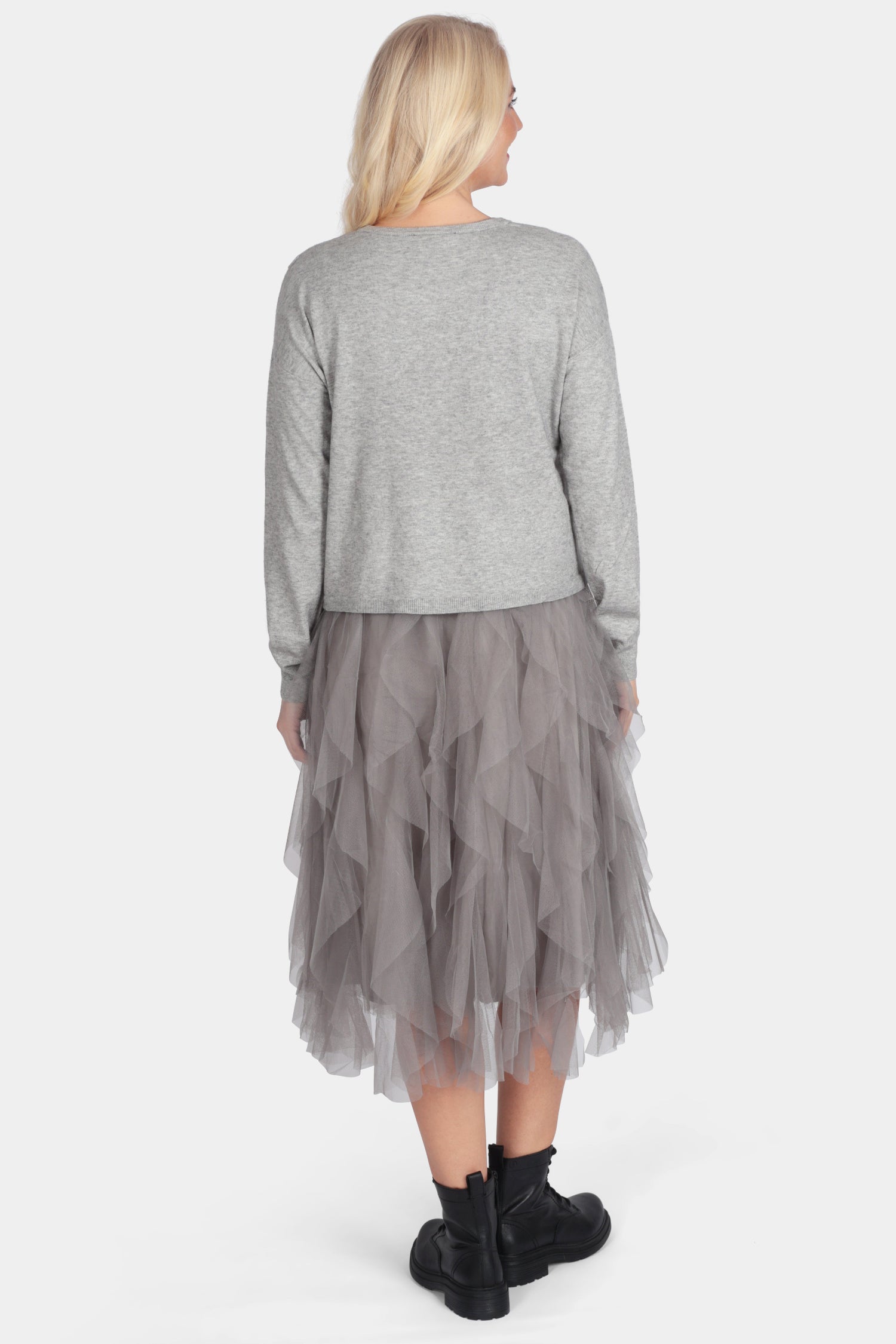 Woman wearing a gray sweater and layered skirt on a white background