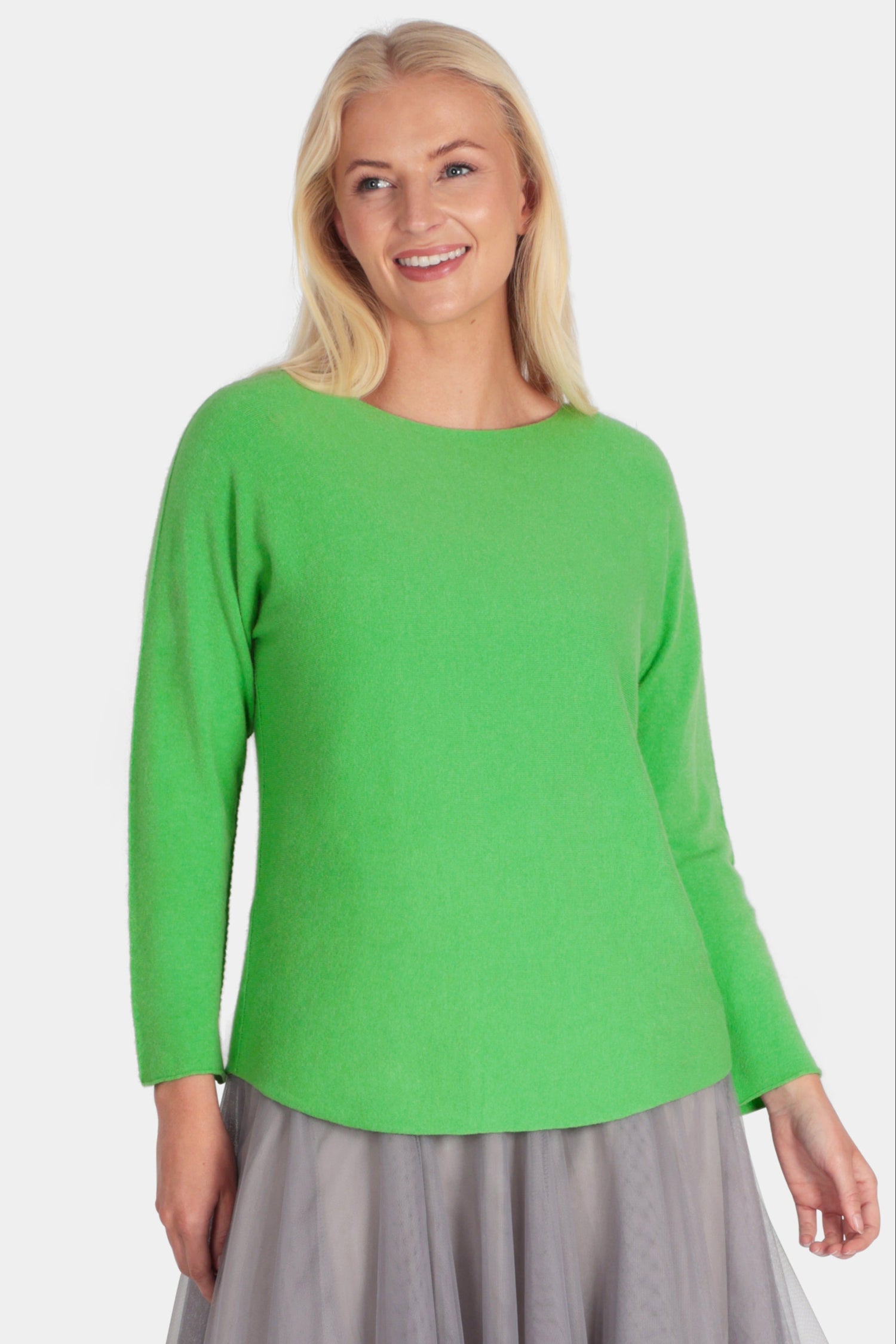 Woman wearing a green top and gray skirt on a white background