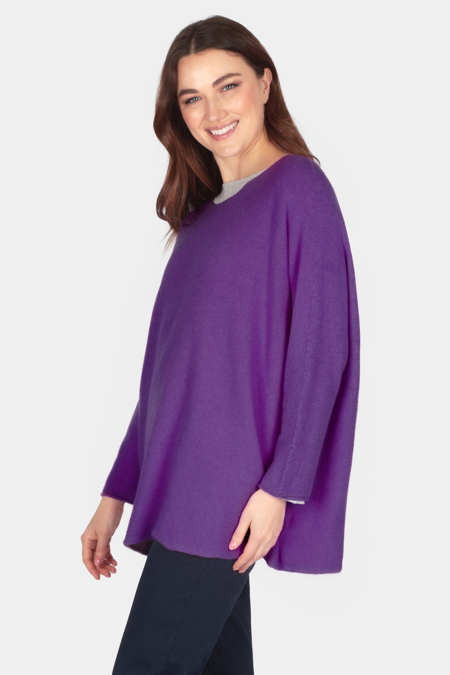 Woman wearing a purple sweater and navy pants on a white background
