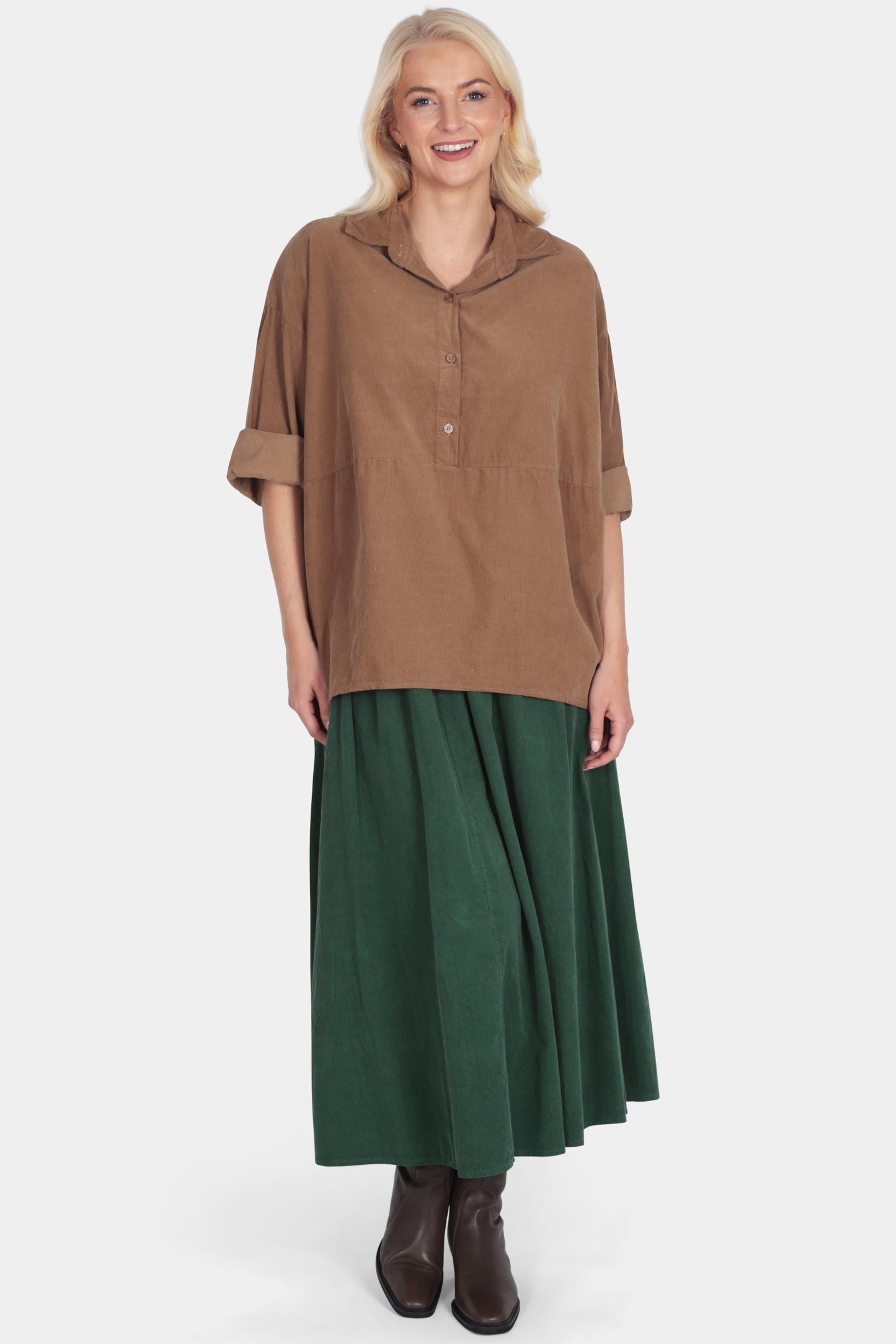 Woman wearing a brown top and green skirt on a white background