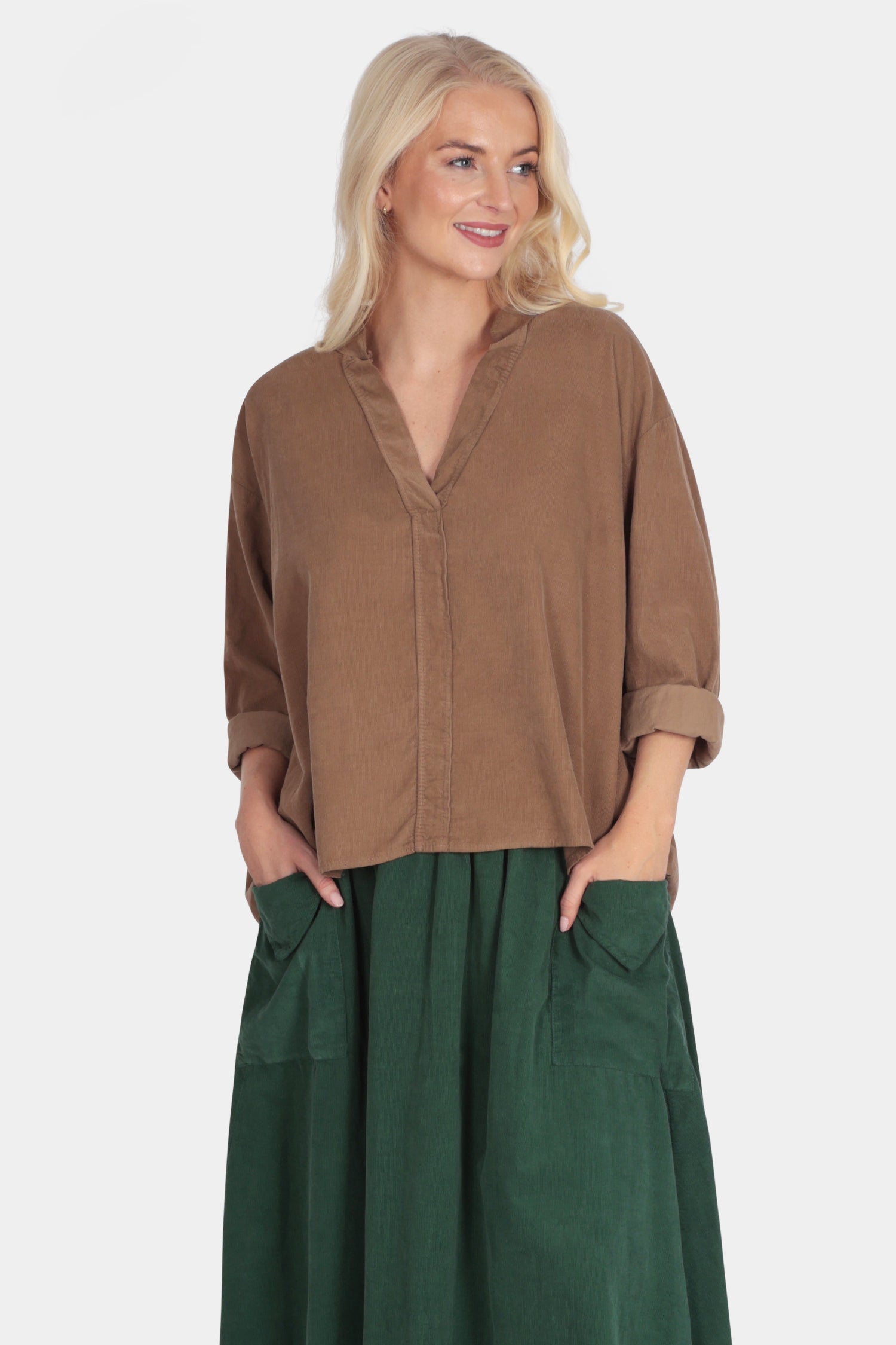 Woman wearing a brown shirt and green skirt on a white background