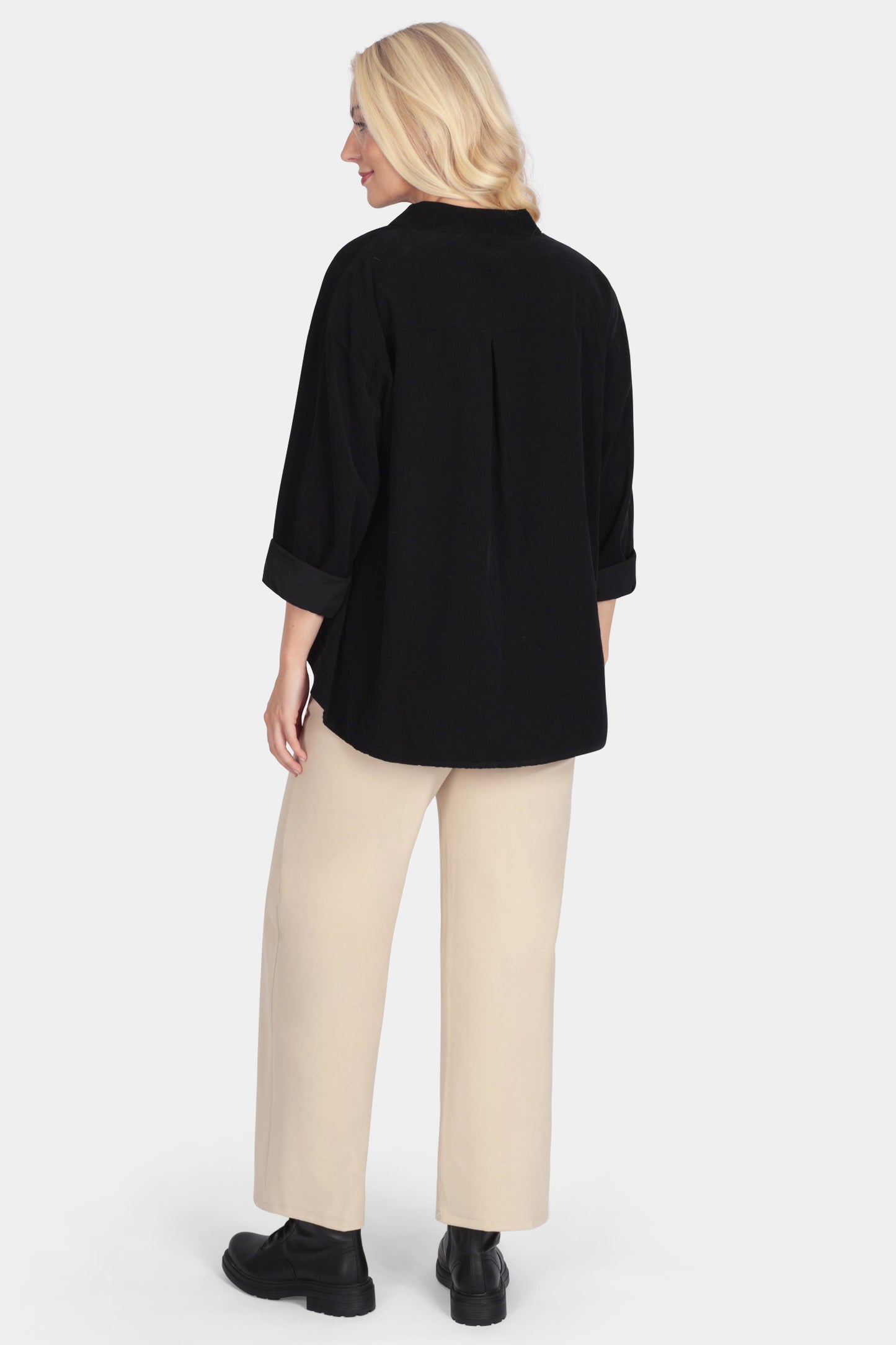 Person wearing a black top and beige pants on a white background