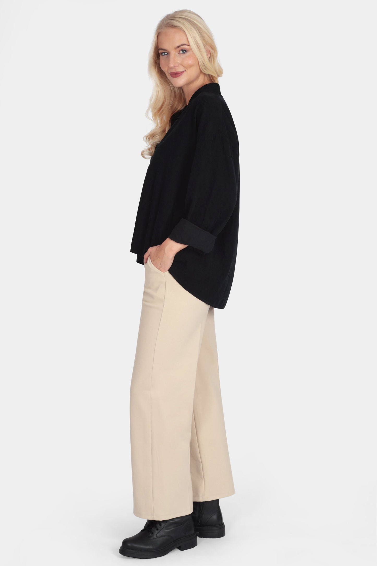 Woman wearing a black top and beige pants on a white background