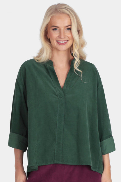 Woman wearing a green top and burgundy pants on a white background