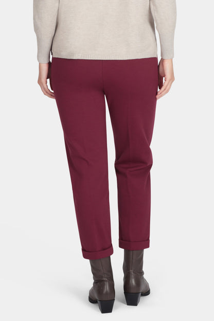 Woman wearing a beige sweater and burgundy pants on a white background