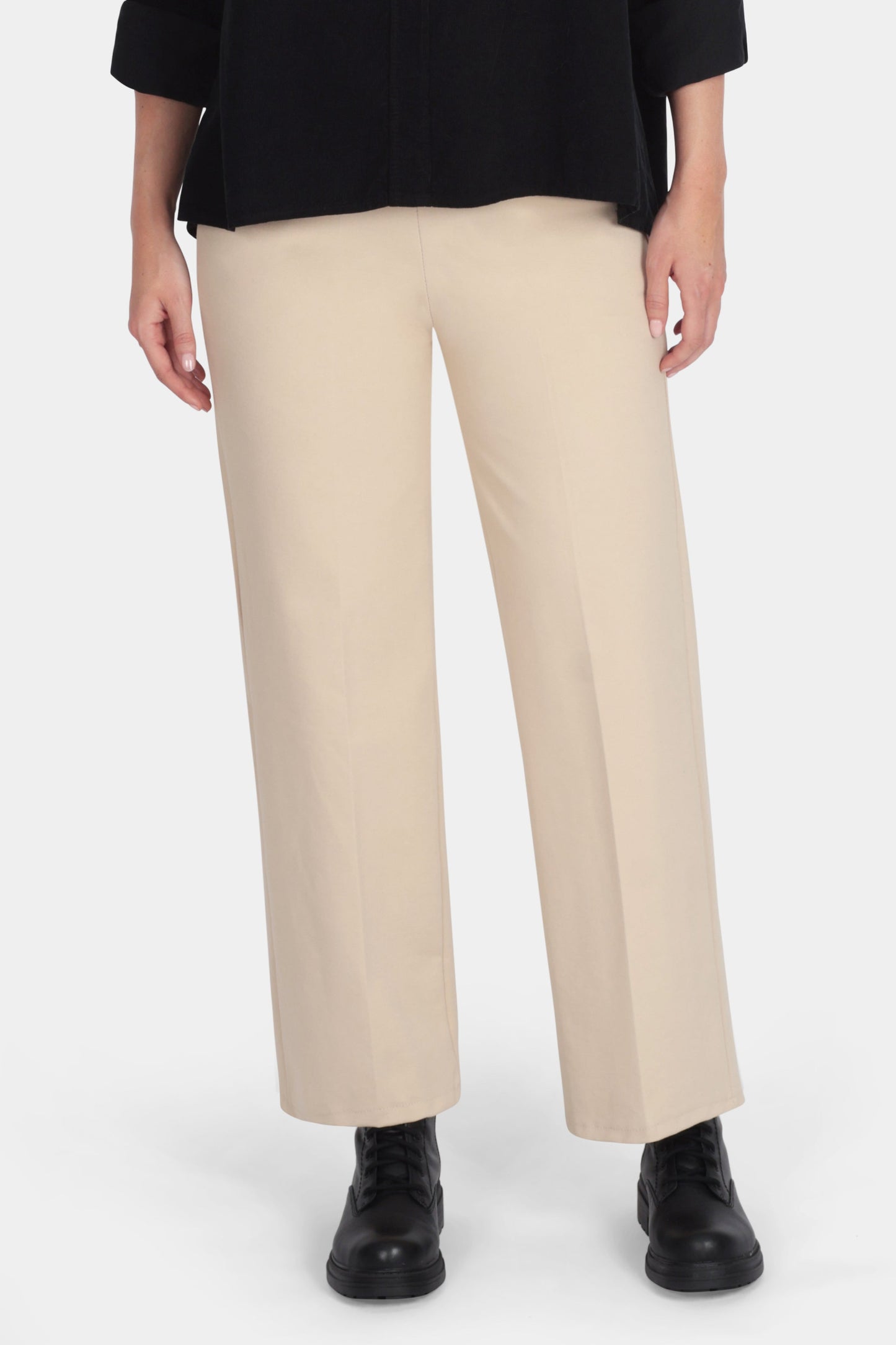 Woman wearing a black blouse and beige pants on a white background