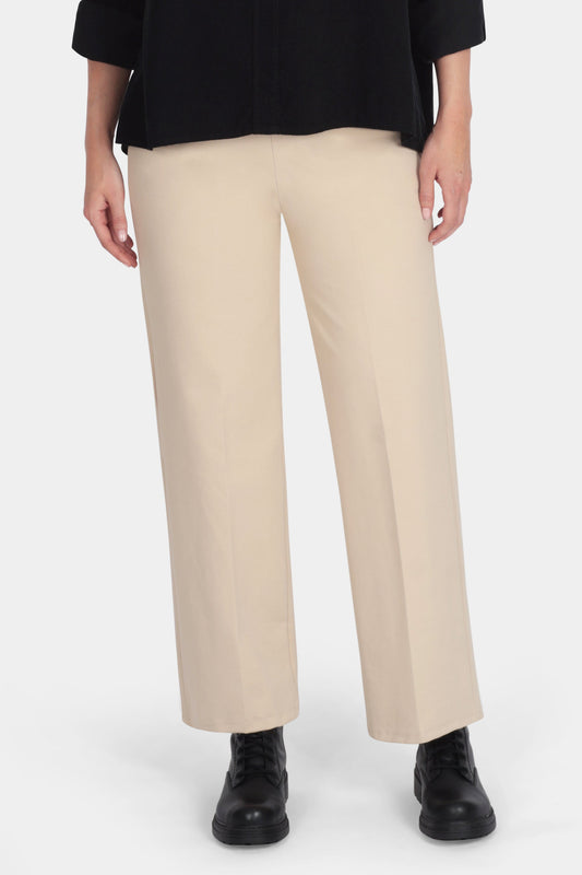 Woman wearing a black blouse and beige pants on a white background